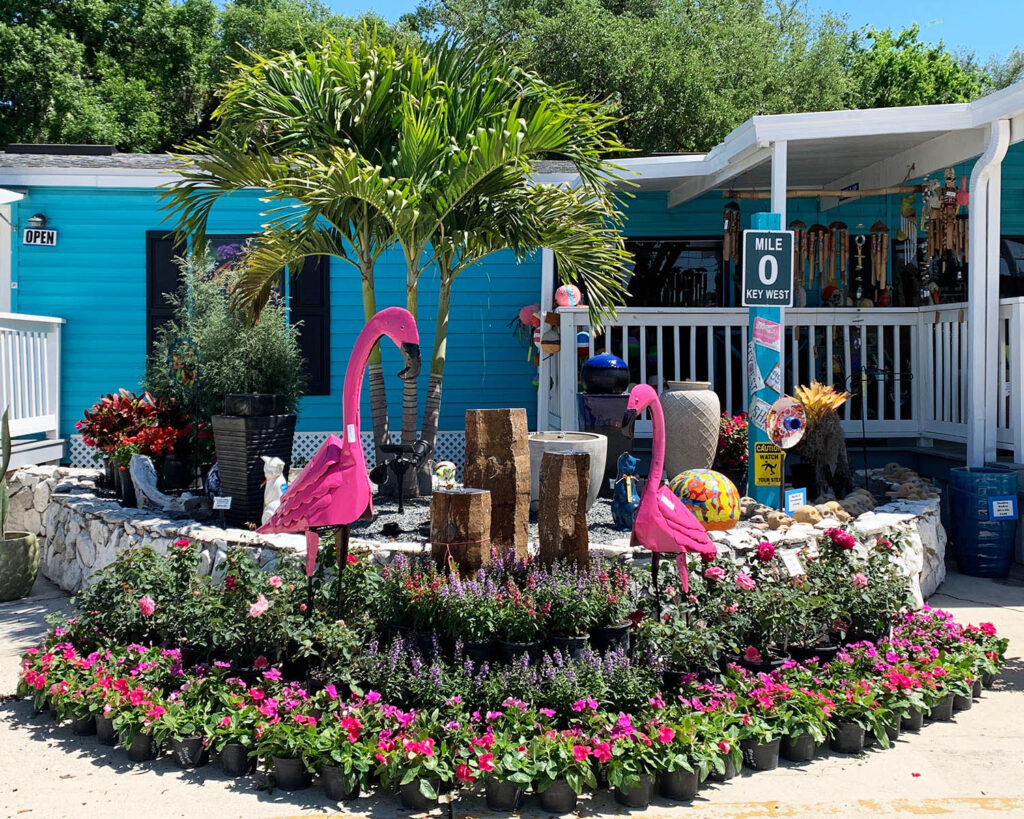 A garden with pink flamingos and flowers.