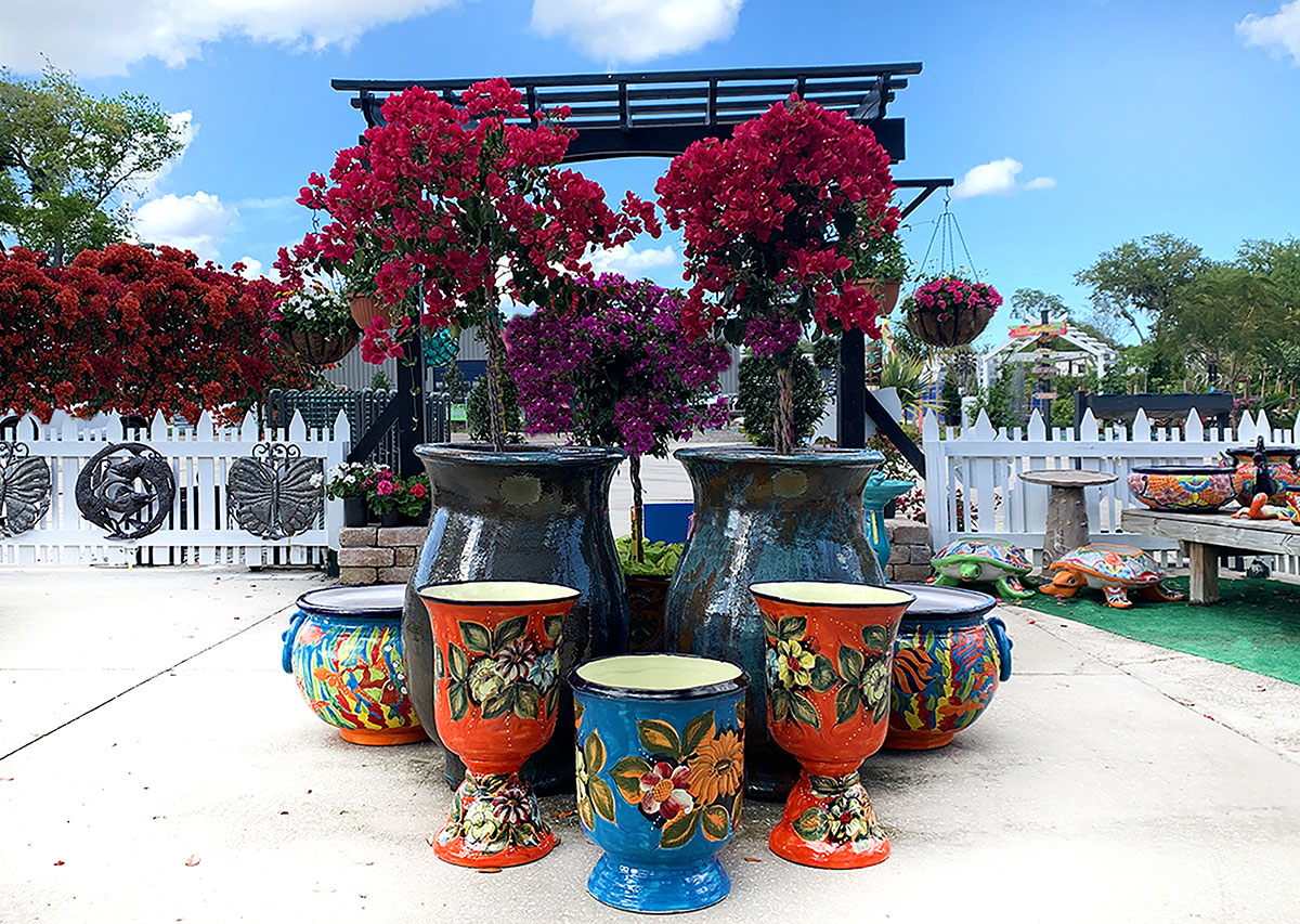 A group of colorful vases sitting on top of a cement floor.