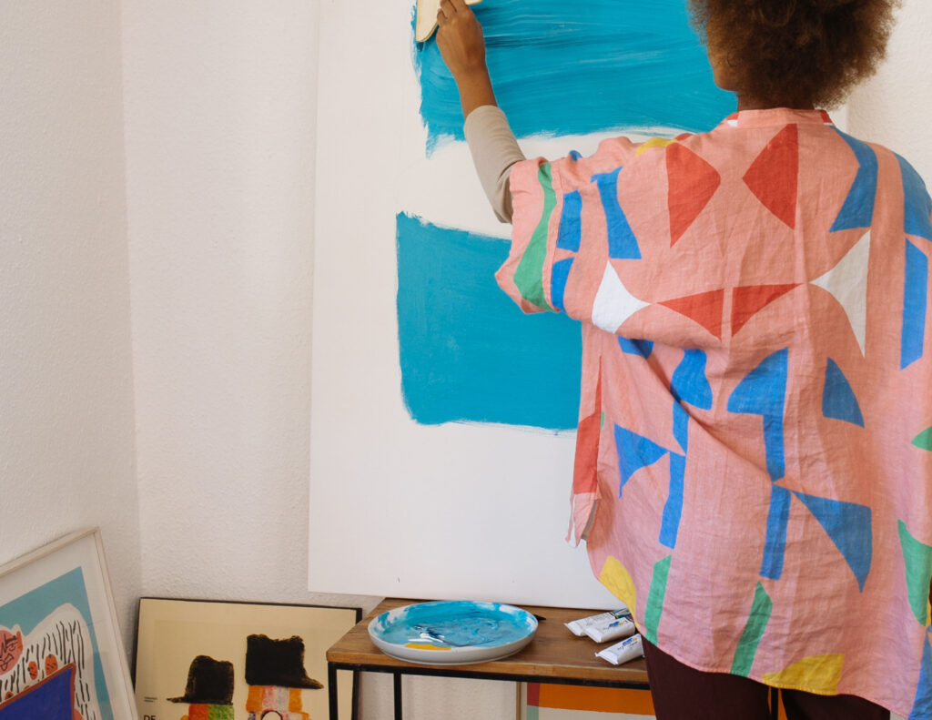 A person painting a wall with blue paint.